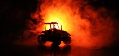 Silhouette of tractor at night with dark foggy background. Toned. Burning vehicle. Decoration