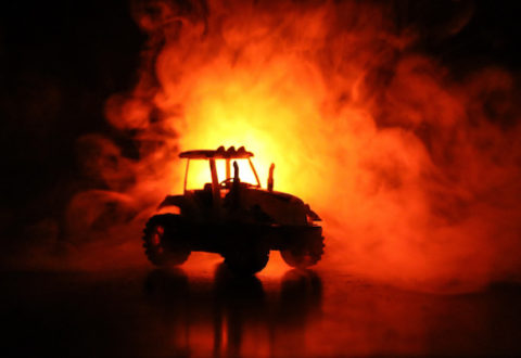 Silhouette of tractor at night with dark foggy background. Toned. Burning vehicle. Decoration